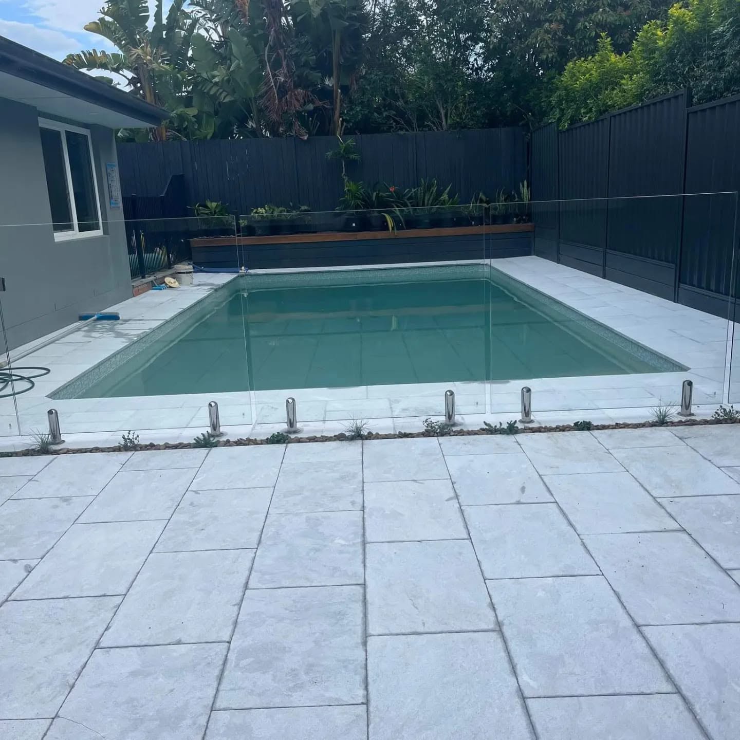 Fibonacci-built pool surround with glass fencing and light stone paving