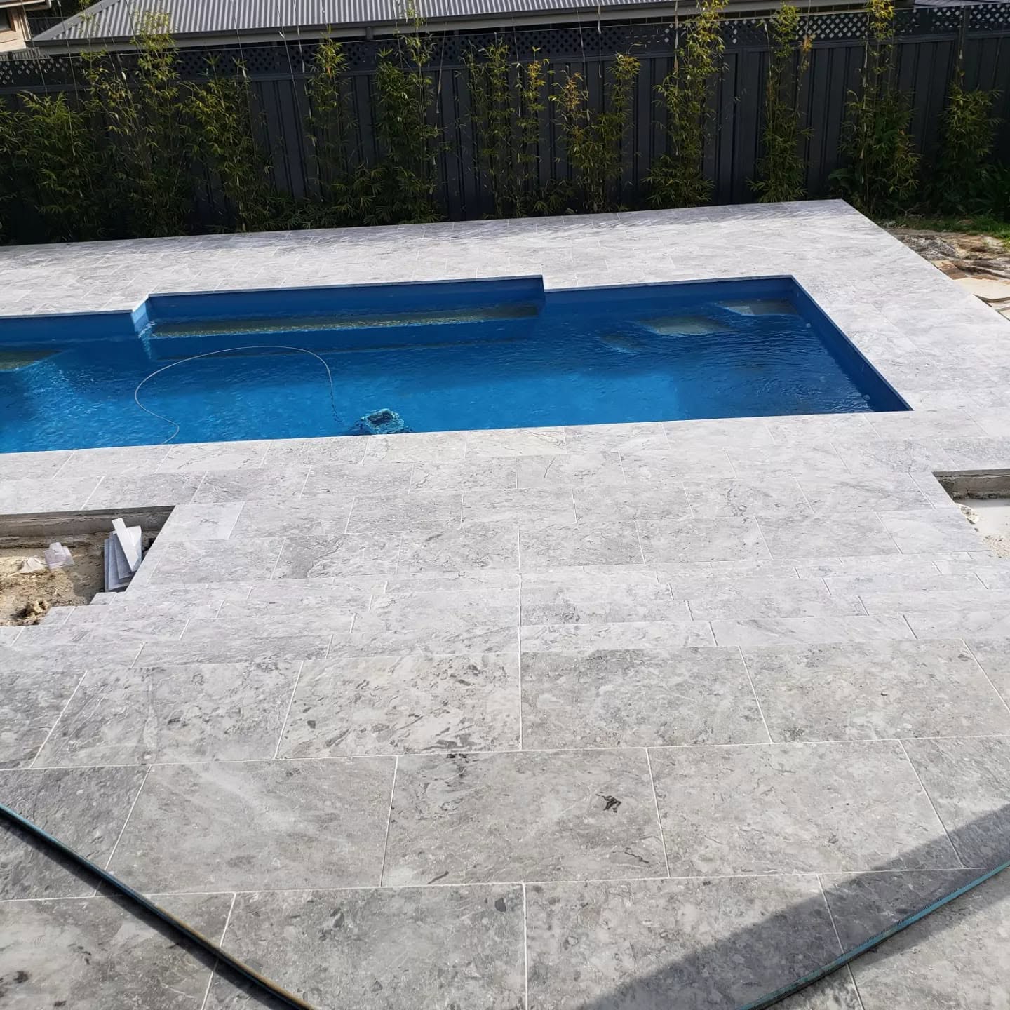 Fibonacci-built pool with travertine paving and timber fencing