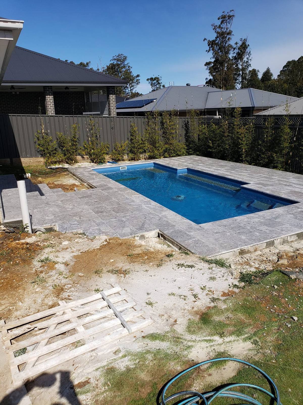 Colorbond fencing beside pool paving and garden bed