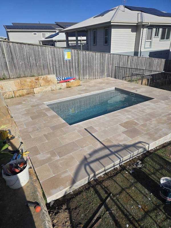 Natural sandstone retaining wall beside a pool